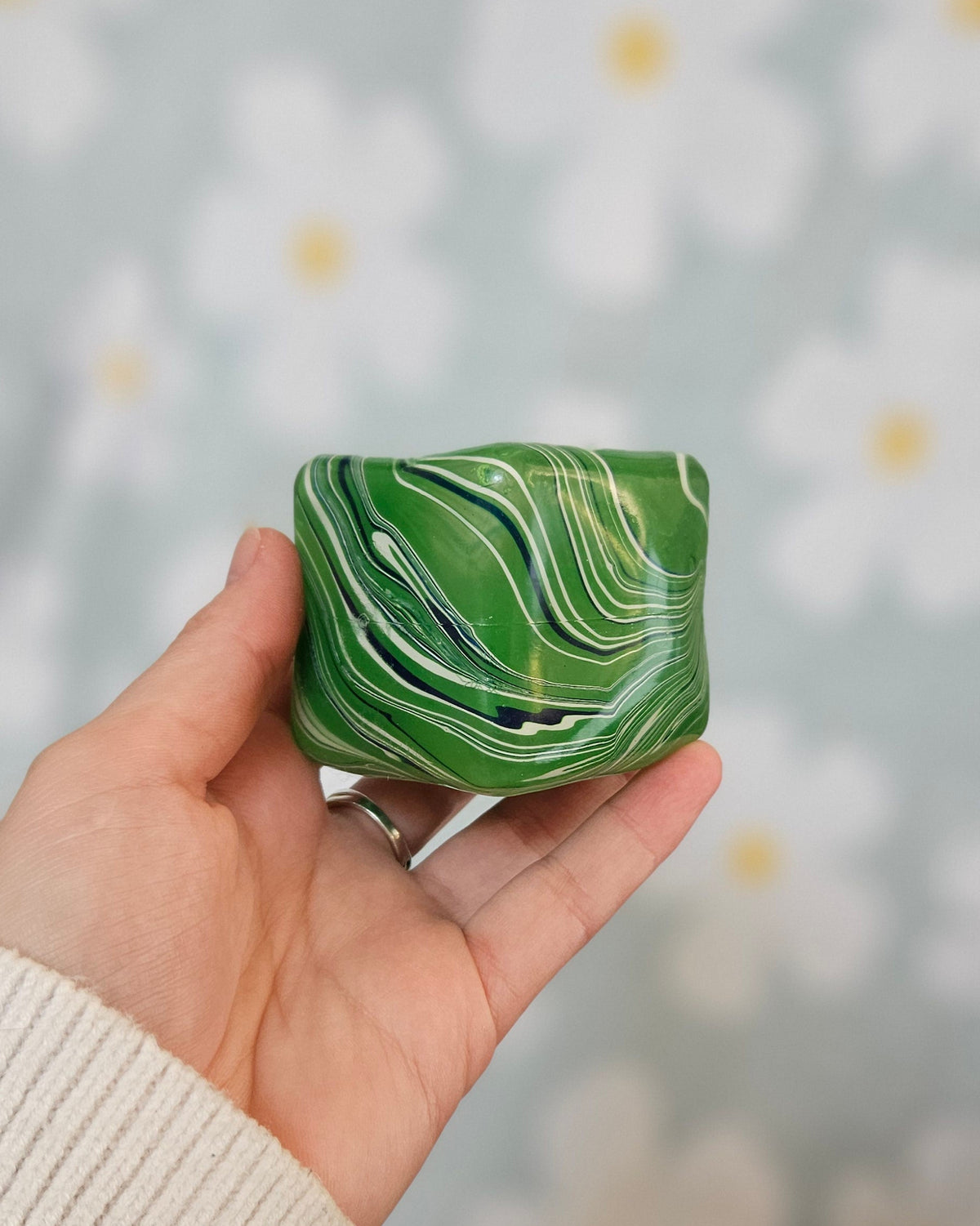 Cube squishy vert marbré de blanc et de bleu, tenu à plat dans une main