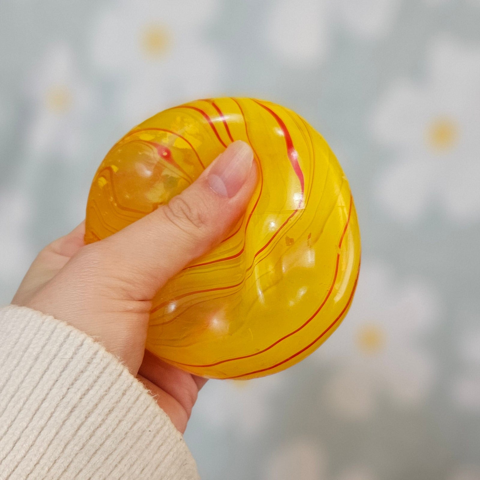 Cube squishy jaune pressé entre les doigts, sa surface se déformant sous la pression du pouce