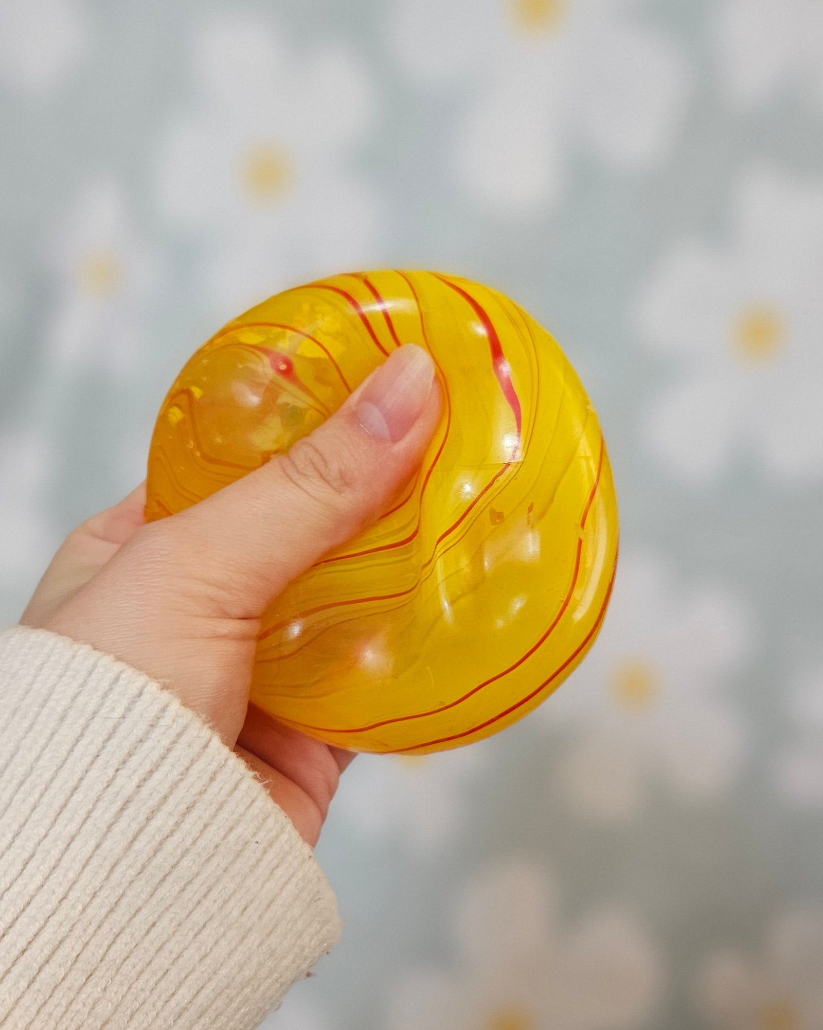 Cube squishy jaune pressé entre les doigts, sa surface se déformant sous la pression du pouce
